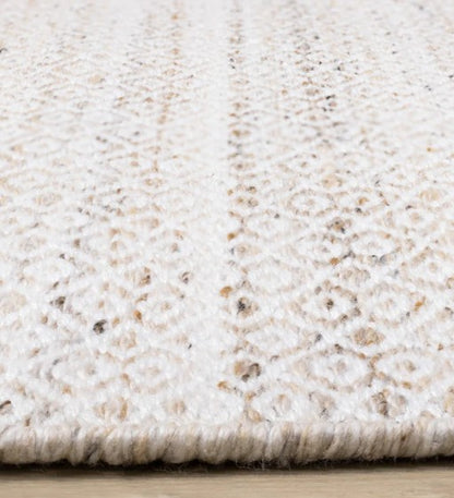 Close-up of a textured beige and white rug on a wooden floor.