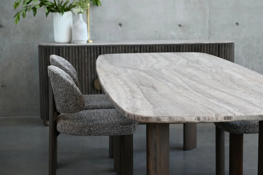 Dining table with marble-like surface and four chairs in a room with concrete walls.