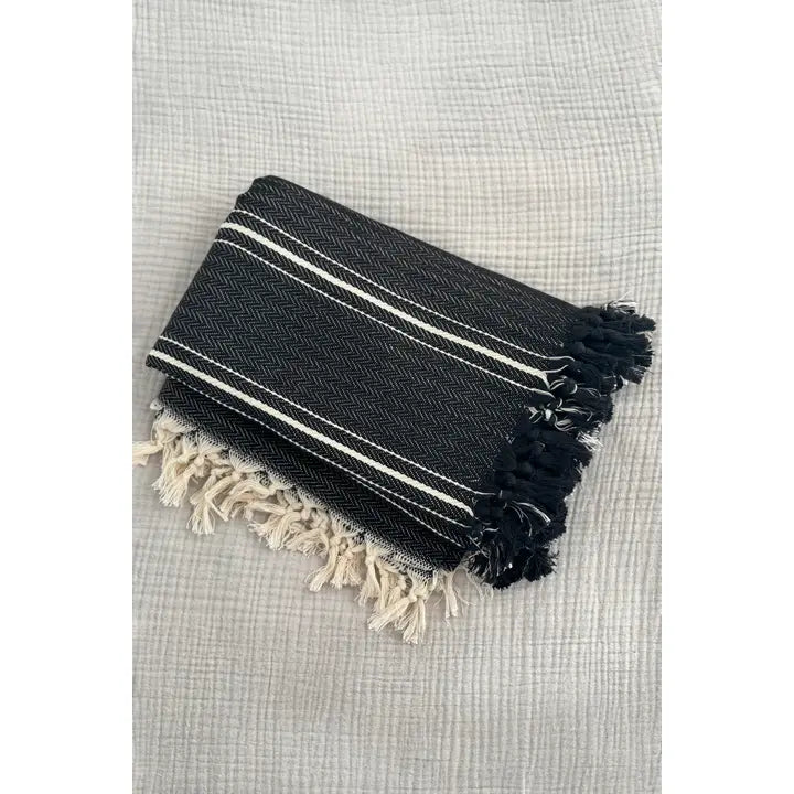 Black and white striped towel with tassels on a textured surface