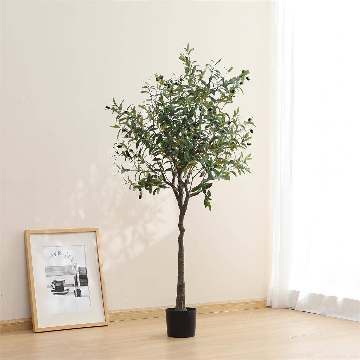 Potted artificial olive tree in a room with a framed picture on the wall.