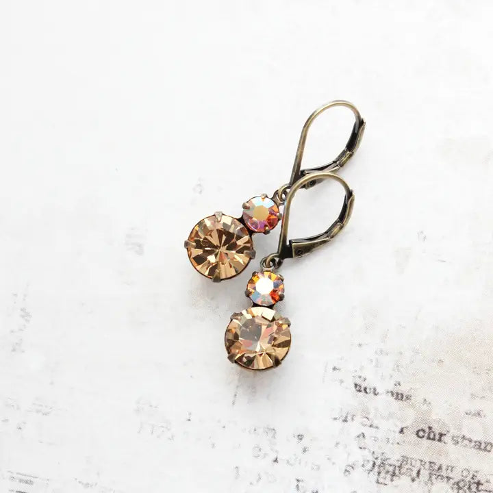 Pair of earrings with multicolored gemstones on a textured white surface