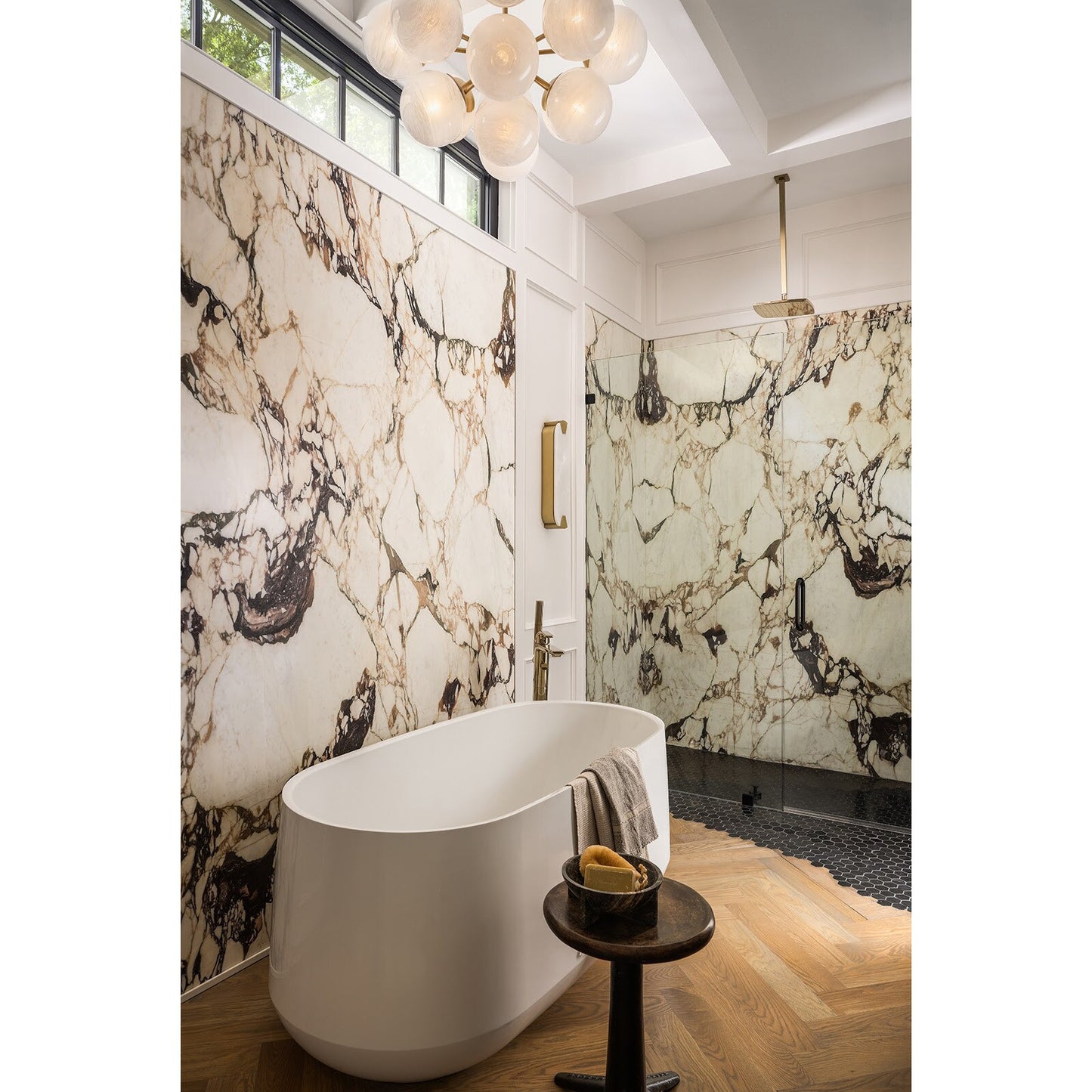 Modern bathroom with marble walls, freestanding bathtub, and decorative elements.