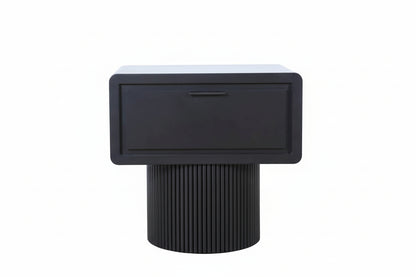 Black side table with a textured cylindrical base on a light wood floor.