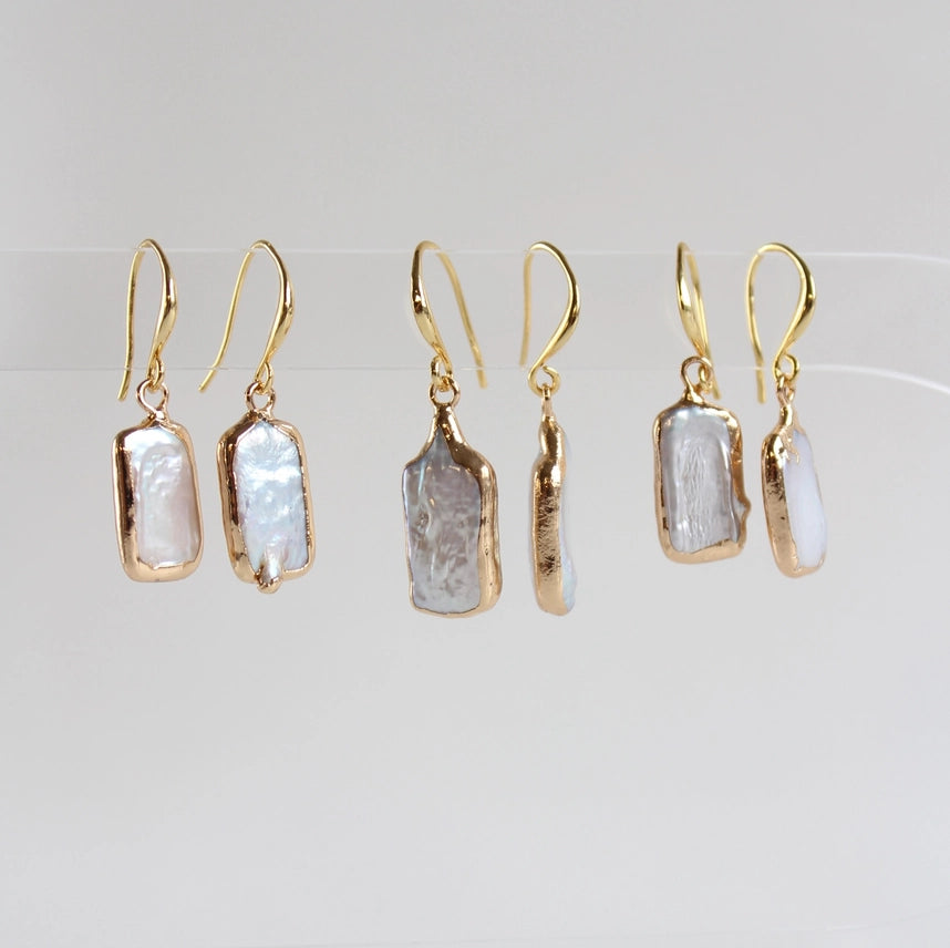 Set of gold earrings with natural stone-like pendants on a light gray background