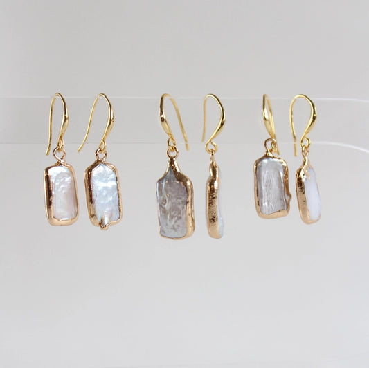 Set of gold earrings with natural stone-like pendants on a light gray background