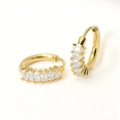 Gold hoop earrings with clear gemstones on a white background