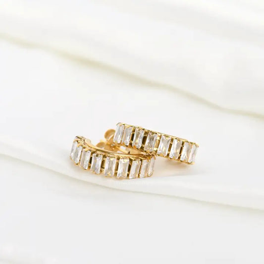Gold hoop earrings with clear gemstones on a white background