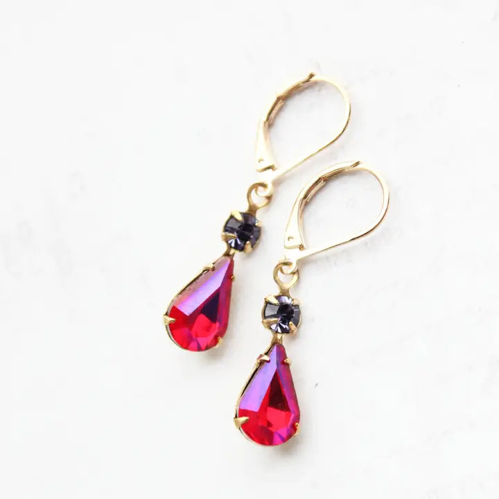 Gold earrings with red teardrop-shaped gemstones on a white background