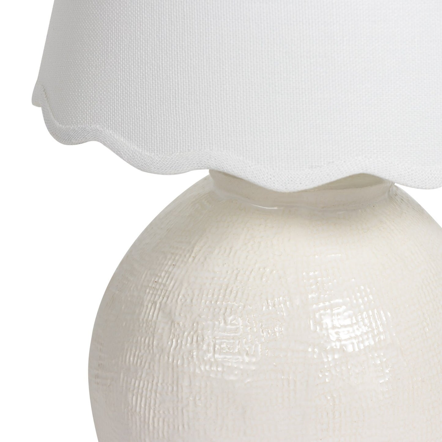 White textured table lamp with a scalloped white shade on a white background