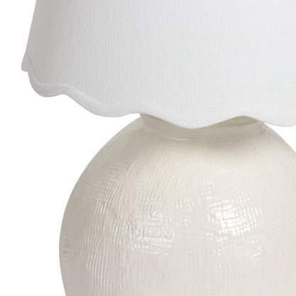 White textured table lamp with a scalloped white shade on a white background