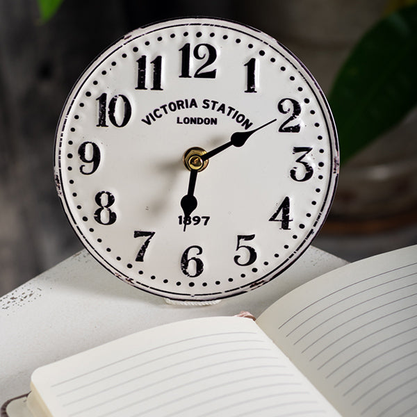 Vintage-style clock with 'Victoria Station London' branding on an open book.