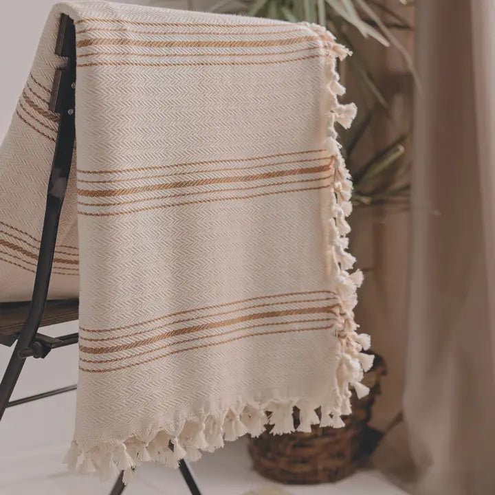Beige towel with brown stripes draped over a chair indoors