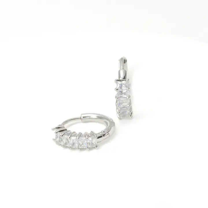 Pair of silver hoop earrings with clear gemstones on a white background