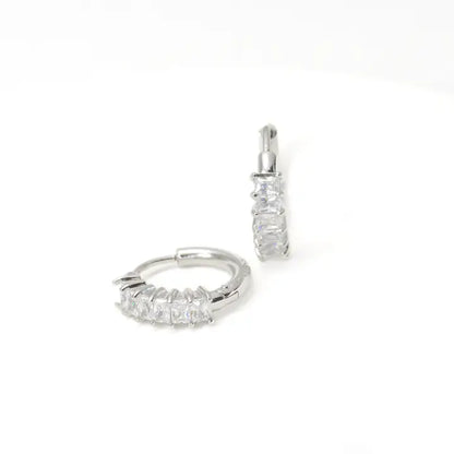 Pair of silver hoop earrings with clear gemstones on a white background