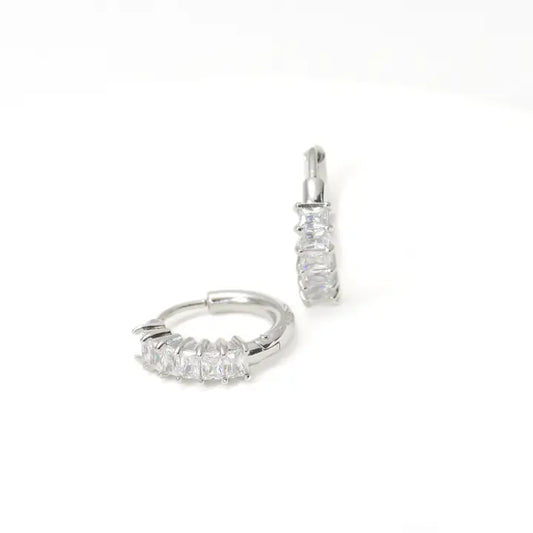 Pair of silver hoop earrings with clear gemstones on a white background